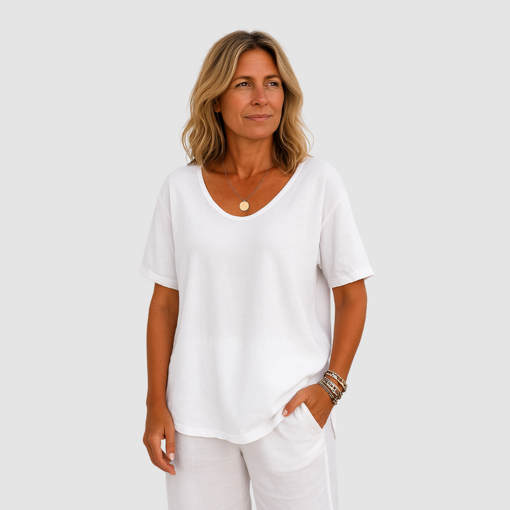 Woman wearing a loose fit white t-shirt and matching white pants in a studio setting.