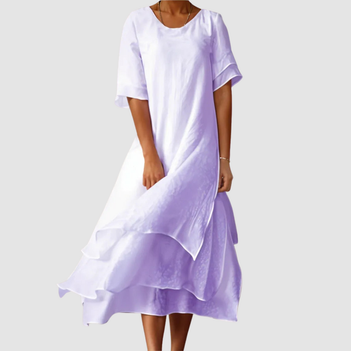 Lavender loose dress with an elegant layered design, displayed by a model on a gray background.