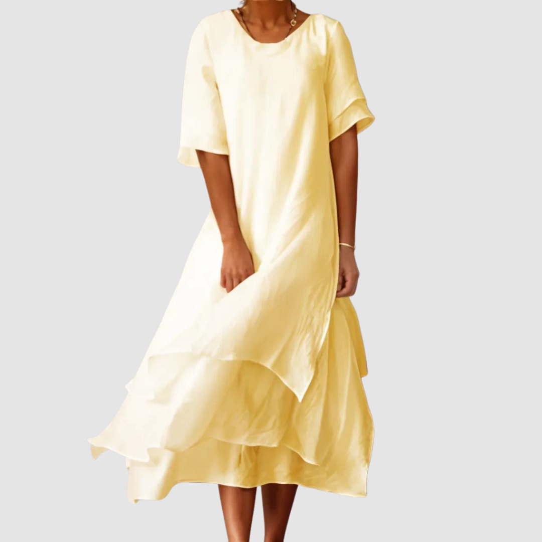 Yellow loose dress with flowing layers, showcased by a model on a simple light gray background.