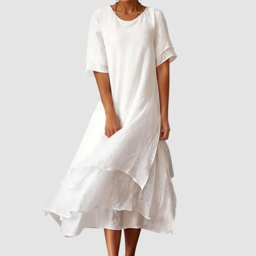 Elegant white loose dress with a flowing layered style, modeled on a pale gray backdrop.