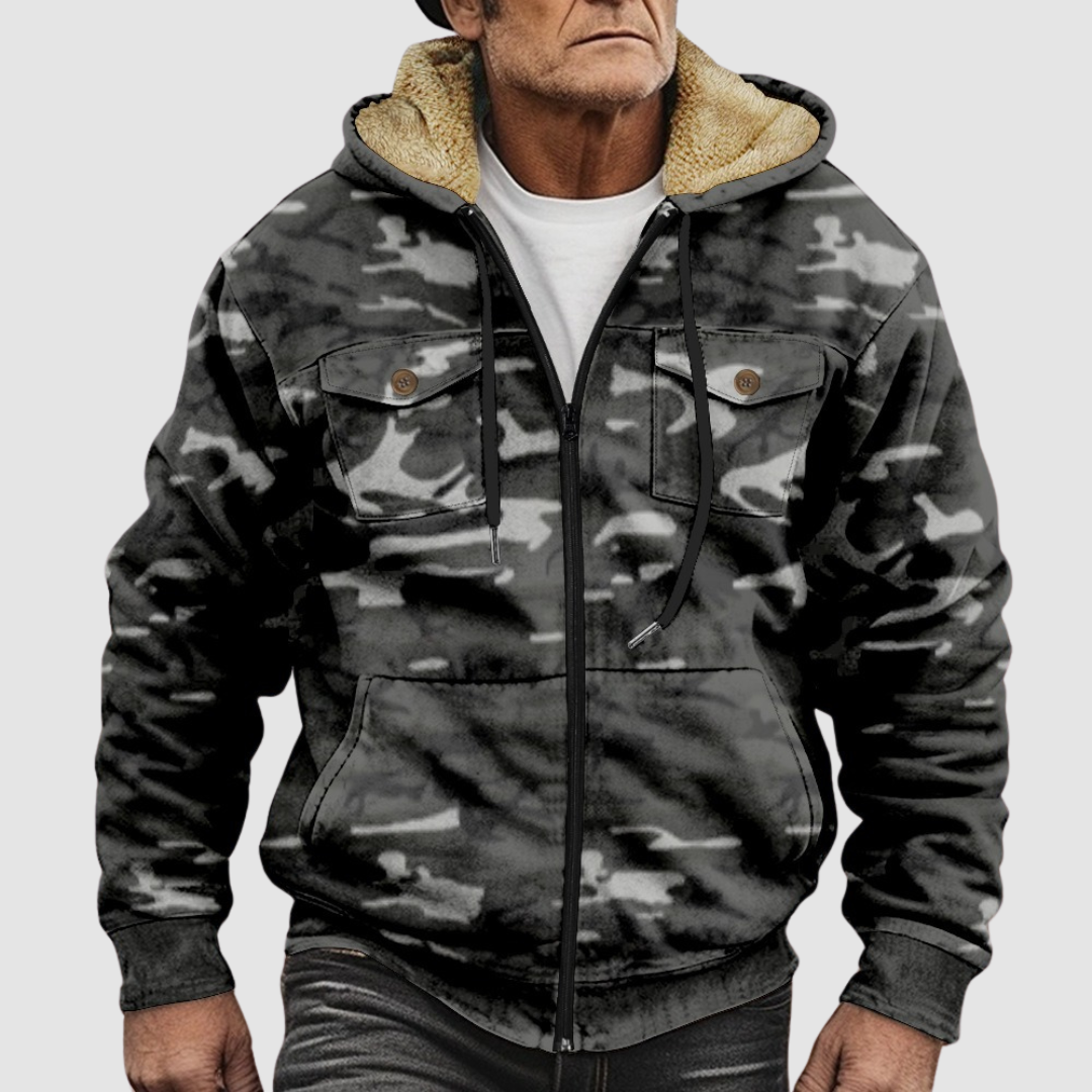 Dark camouflage jacket featuring furry hood inside, zip front, and chest flap pockets on a neutral gray background.