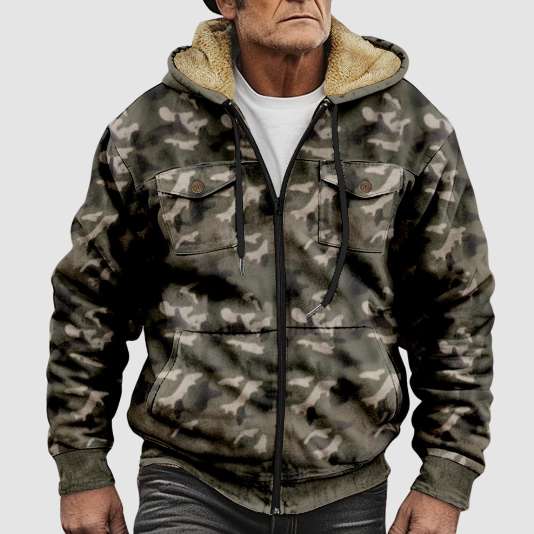Light camouflage jacket with fluffy hood lining, zip front, and chest pockets worn by a model on a plain gray backdrop.