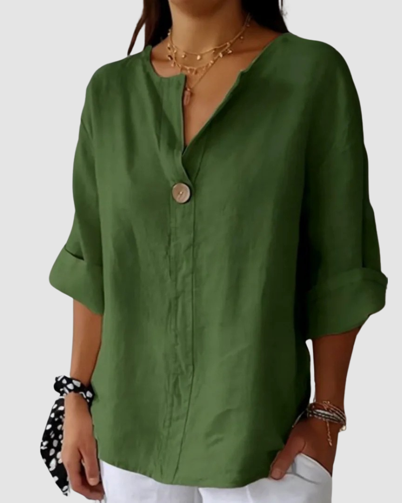 Green blouse with button detail, relaxed fit, cuffed sleeves, styled with white pants and black tie in studio.