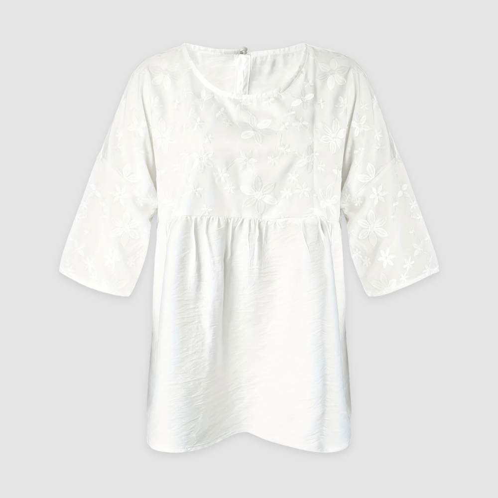 White loose fit shirt with floral pattern and three-quarter sleeves displayed on a light gray background.
