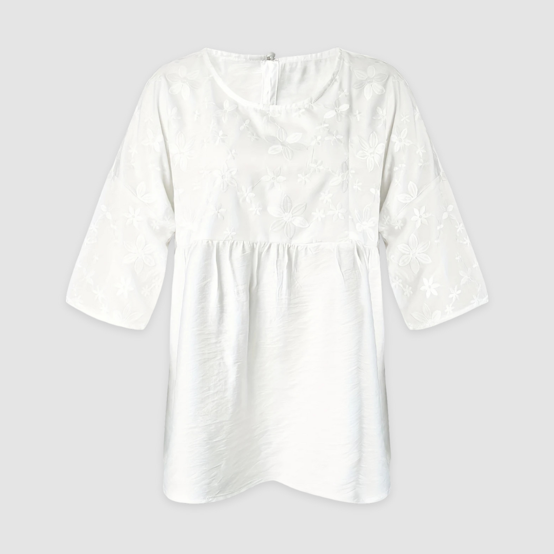 White loose fit shirt with floral pattern and three-quarter sleeves displayed on a light gray background.