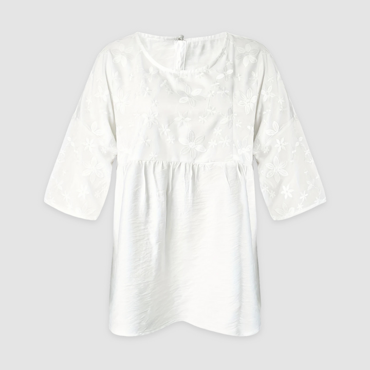 White loose fit shirt with floral pattern and three-quarter sleeves displayed on a light gray background.