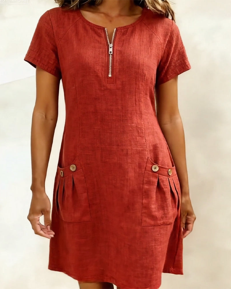 Red short-sleeve dress with zipper and buttoned pockets, studio backdrop.