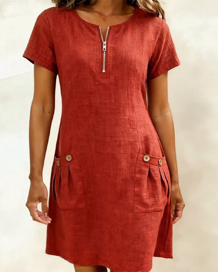 Red short-sleeve dress with zipper and buttoned pockets, studio backdrop.