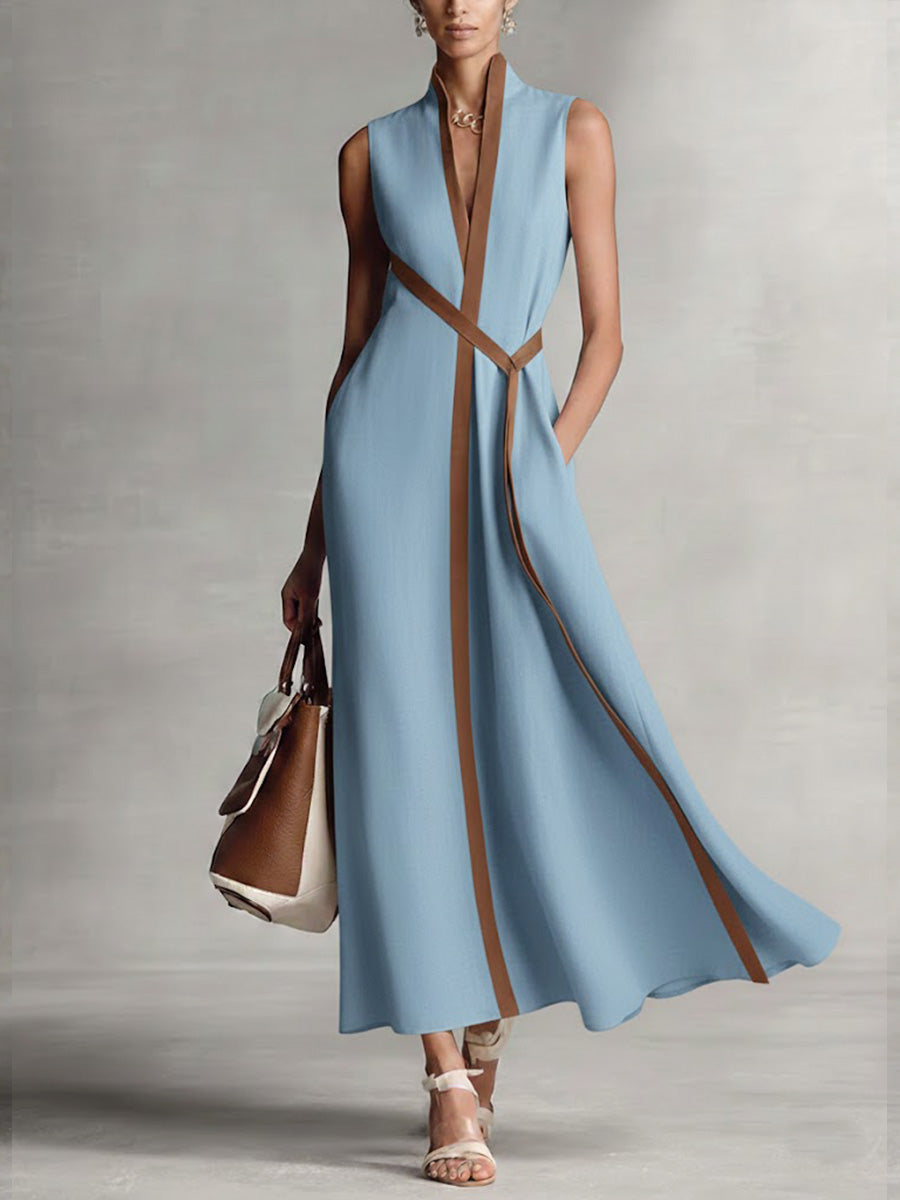 Stylish sleeveless blue maxi dress with brown trim, paired with a handbag and sandals in a studio setting.