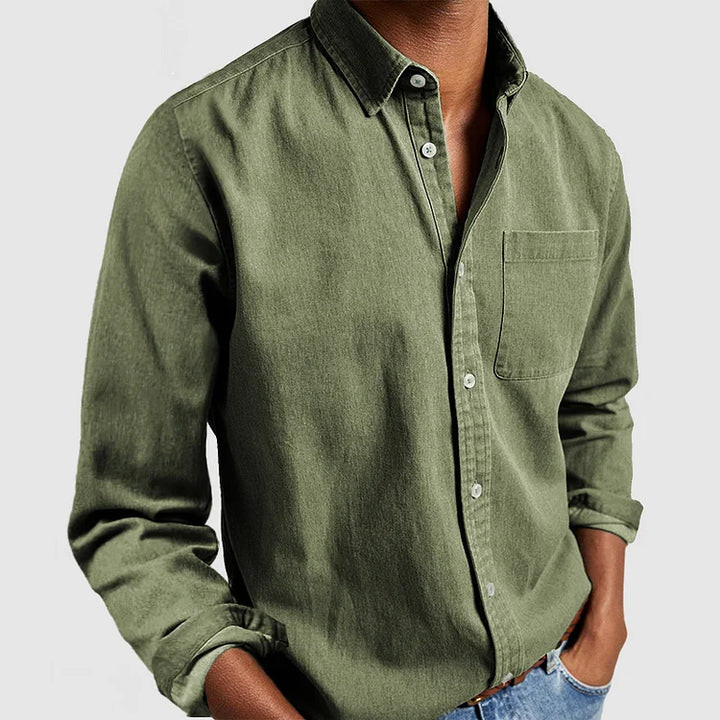Green button-up shirt with front pocket and rolled sleeves, styled with hands in pockets; gray background.