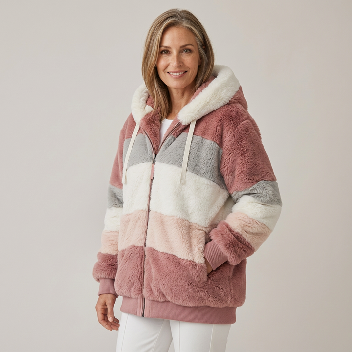 Woman wearing a plush, multicolored hooded jacket in white, pink, and beige stripes, in a studio setting.