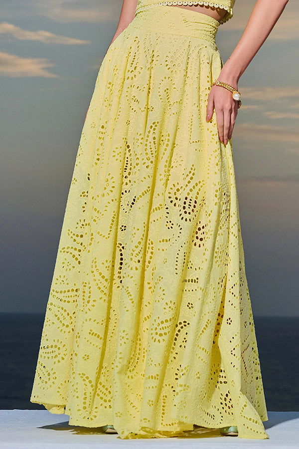 Side view of a yellow embroidered high-waist maxi skirt worn by a model against a sunset backdrop.