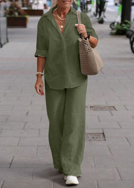 Woman wearing a green two-piece set with rolled cuffs, walking down the street carrying a beige woven bag.