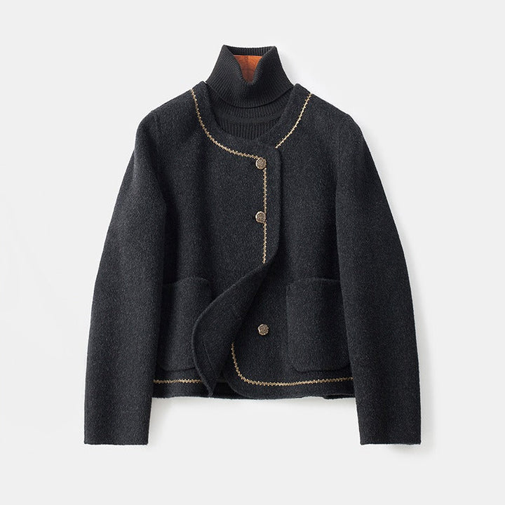 Black cashmere coat with decorative trim and buttons, layered over a dark turtleneck, on a white background.
