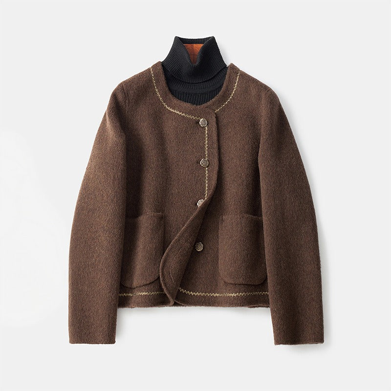 Brown cashmere coat with decorative trim and buttons, layered over a dark turtleneck, on a white background.