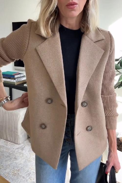 Beige knitted blazer with double-breasted buttons, worn over a black top and jeans in a well-lit indoor setting.