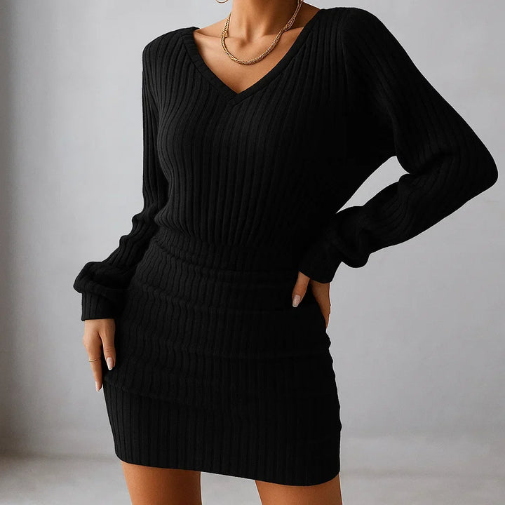 Black knit dress with ribbed texture and V-neckline, styled indoors against a neutral background.