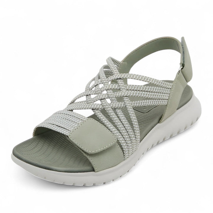 Light green orthopedic comfort sandal with crisscross straps, displayed in a studio setting.