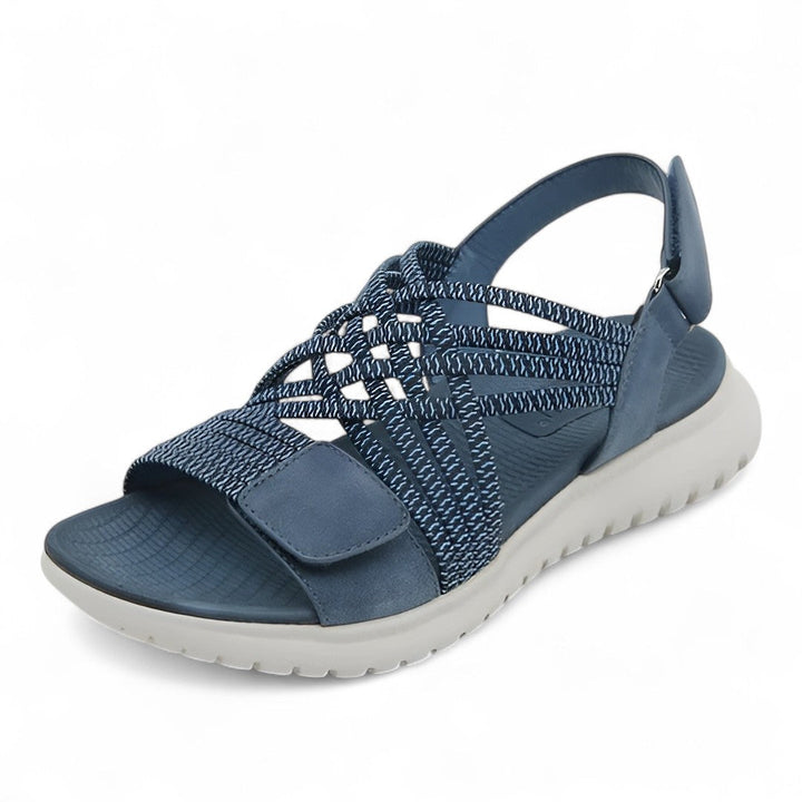 Blue orthopedic comfort sandal with crisscross straps, displayed in a studio setting.