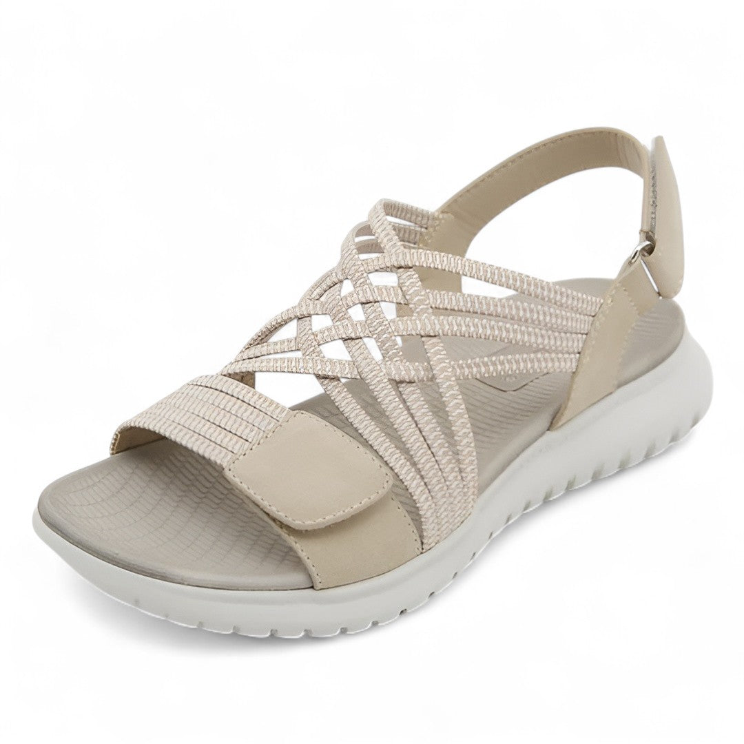 Beige orthopedic comfort sandal with crisscross straps, displayed in a studio setting.