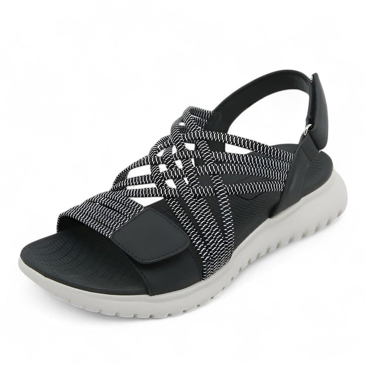 Black orthopedic comfort sandal with crisscross straps, displayed in a studio setting.