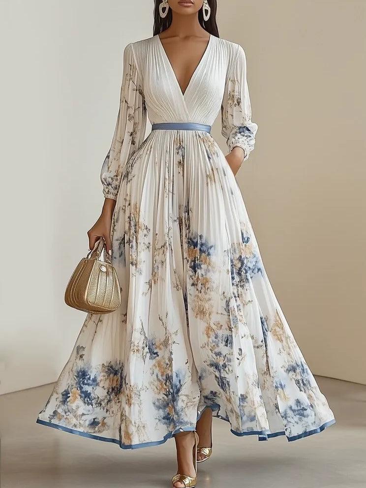 Elegant pleated floral maxi dress with blue and gold accents, deep V-neck, long sleeves, studio setting.
