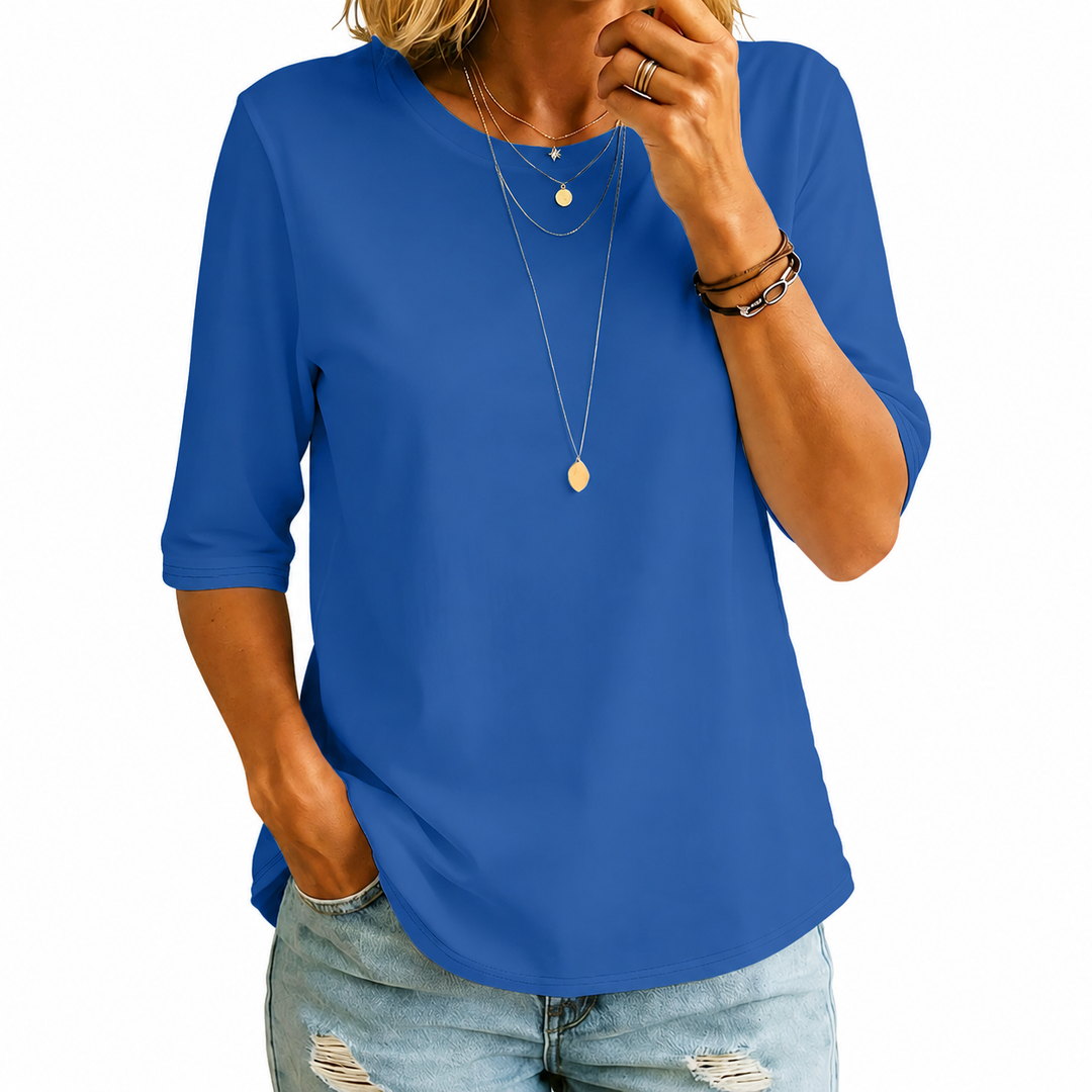 Royal blue three-quarter sleeve tee with layered necklaces, worn with light blue distressed jeans, against a white background.