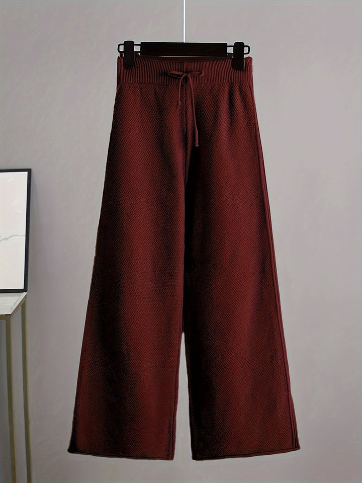 Burgundy knit pants with a relaxed fit and drawstring on a hanger, gray background.