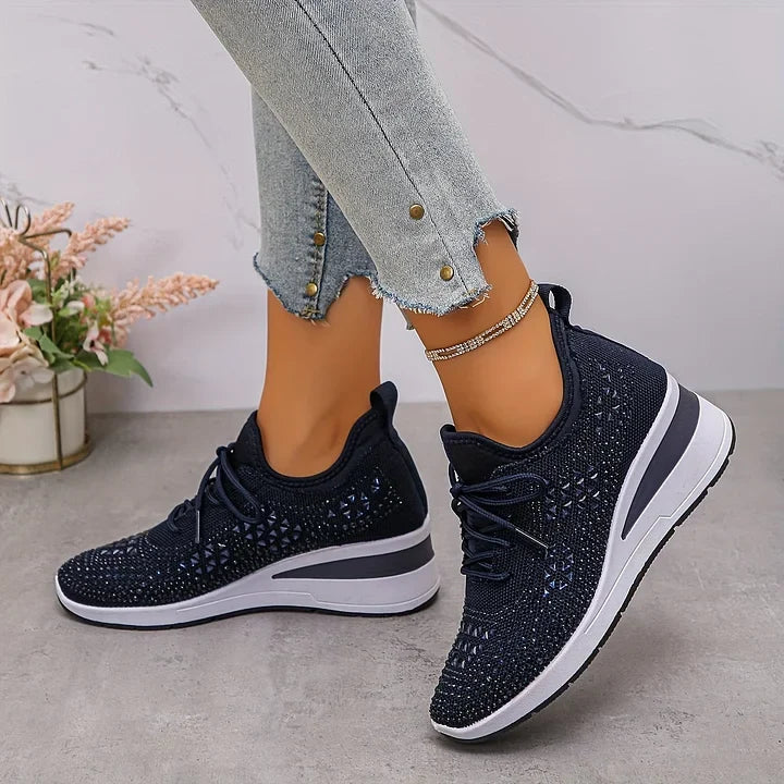 Navy blue sparkling orthopedic sneakers styled with jeans in a minimalistic indoor environment.