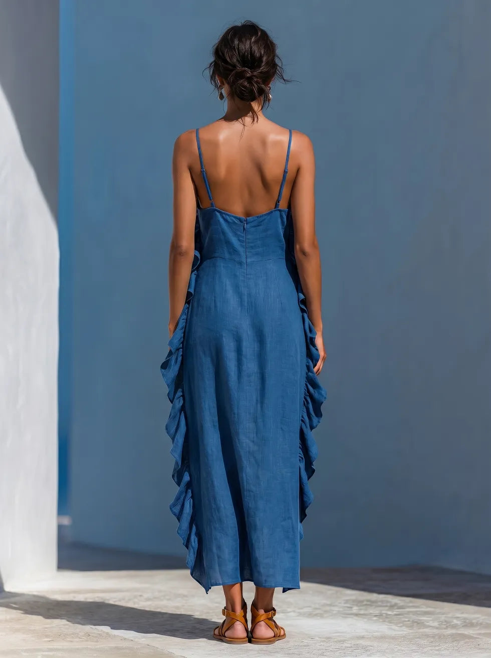 Full back view of blue maxi dress with ruffles, worn with sandals, in a sunlit, minimalistic outdoor setting.