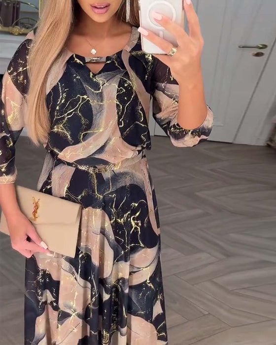 Trendy black and beige patterned dress, styled with clutch in sophisticated indoor setting with parquet flooring.