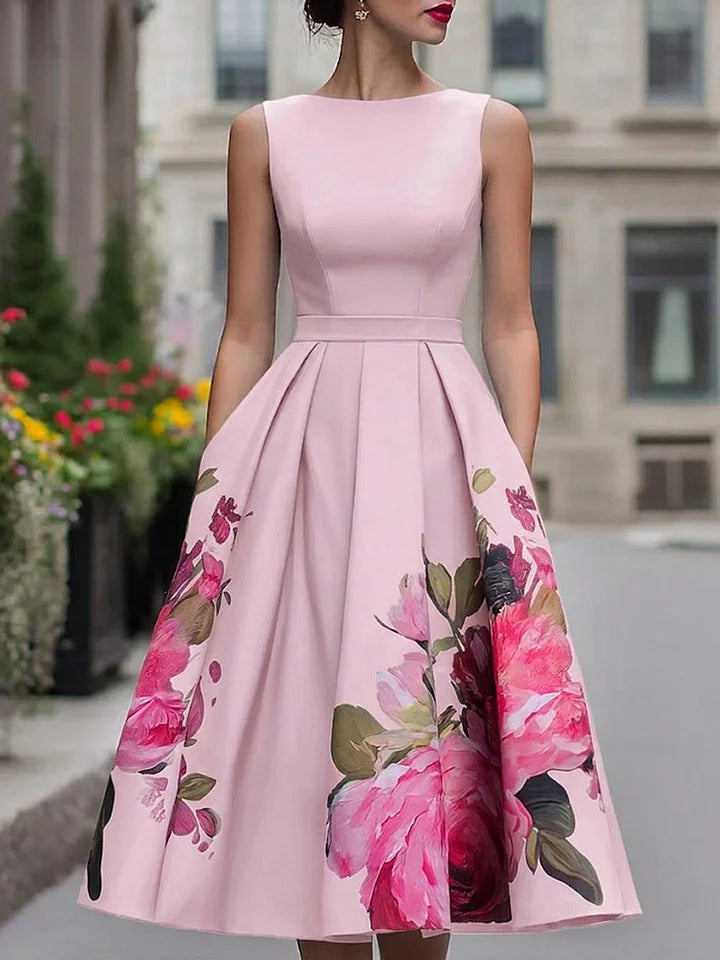 Elegant pink midi dress with vibrant floral pattern, worn by model in urban background.