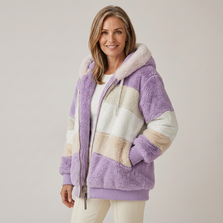 Woman wearing a plush, multicolored hooded jacket in white, purple, and beige stripes, in a studio setting.