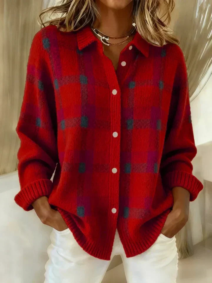 Red plaid button-up shirt featuring a casual fit, worn with white bottoms, with an indoor setting in the background.