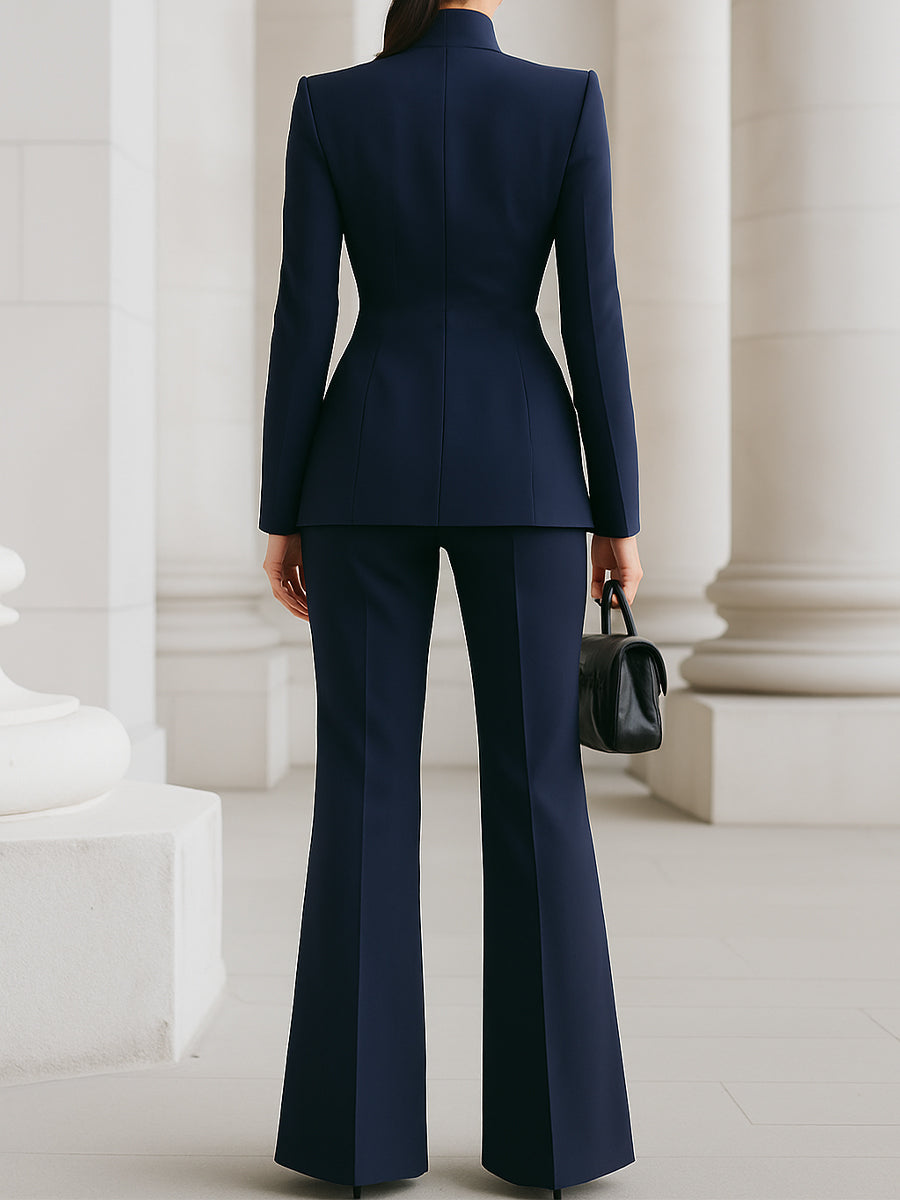 Back view of dark blue tailored two-piece set featuring a fitted jacket and flared pants in an elegant architectural setting.