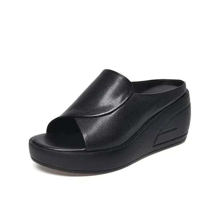 Black orthopedic slip-on wedge sandal with a smooth curved strap, displayed in a studio setting.