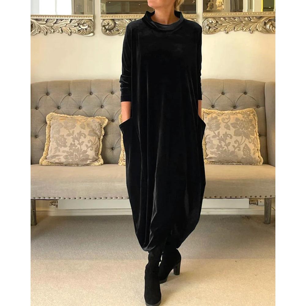 Black flowing suede dress with pockets, displayed in an indoor setting with a sophisticated gray tufted sofa.