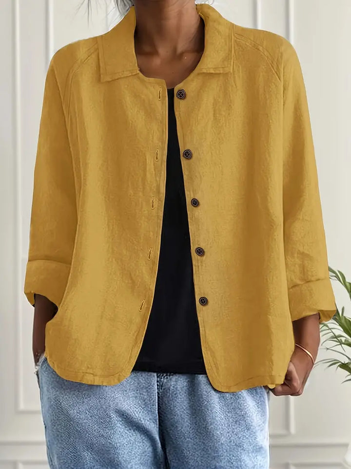Mustard yellow button-up top with rolled sleeves, worn over black shirt in an indoor setting.
