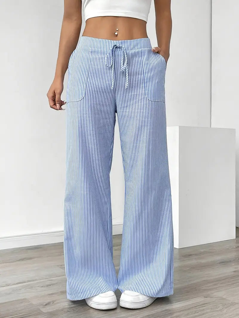 Blue and white striped relaxed pants with drawstring waist, displayed indoors, paired with white sneakers and crop top.