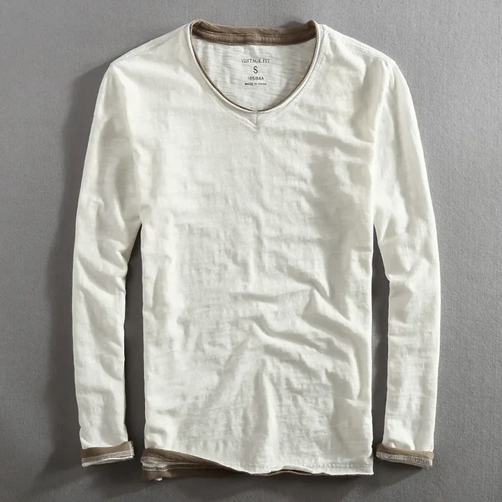 White long sleeve shirt with contrast trim, laying flat on a gray surface.