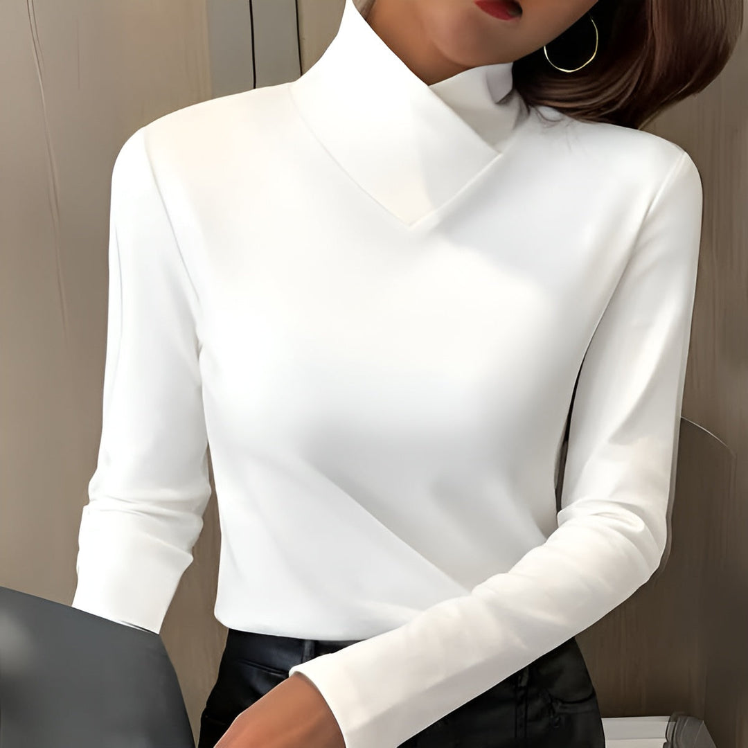 White high-neck sweater with long sleeves, worn indoors. Neutral-toned background with subtle lighting.