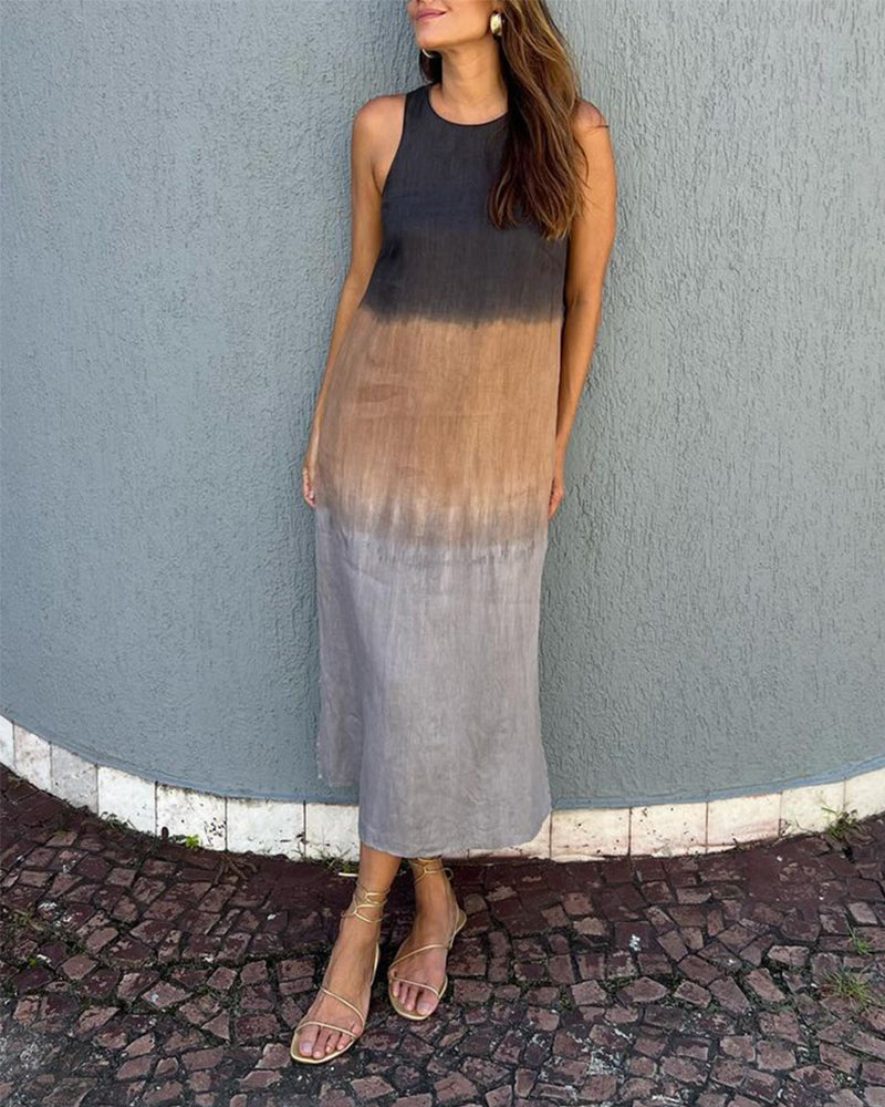 Woman in ombre black to brown sleeveless dress standing against a textured wall outdoors.
