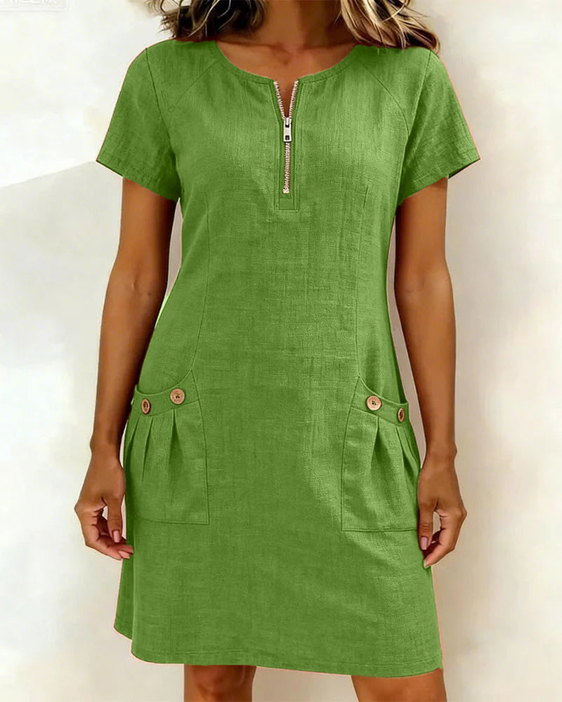 Green short-sleeve dress with zipper front and buttoned pockets in a studio setting.