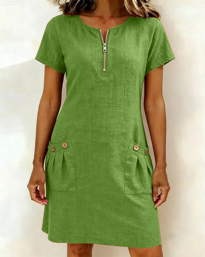 Green short-sleeve dress with zipper front and buttoned pockets in a studio setting.