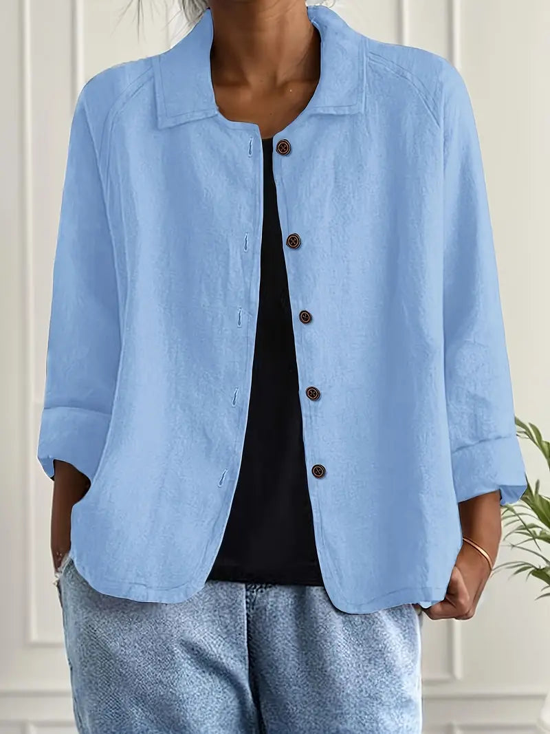Light blue button-up top with rolled sleeves, worn over black shirt in an indoor setting.