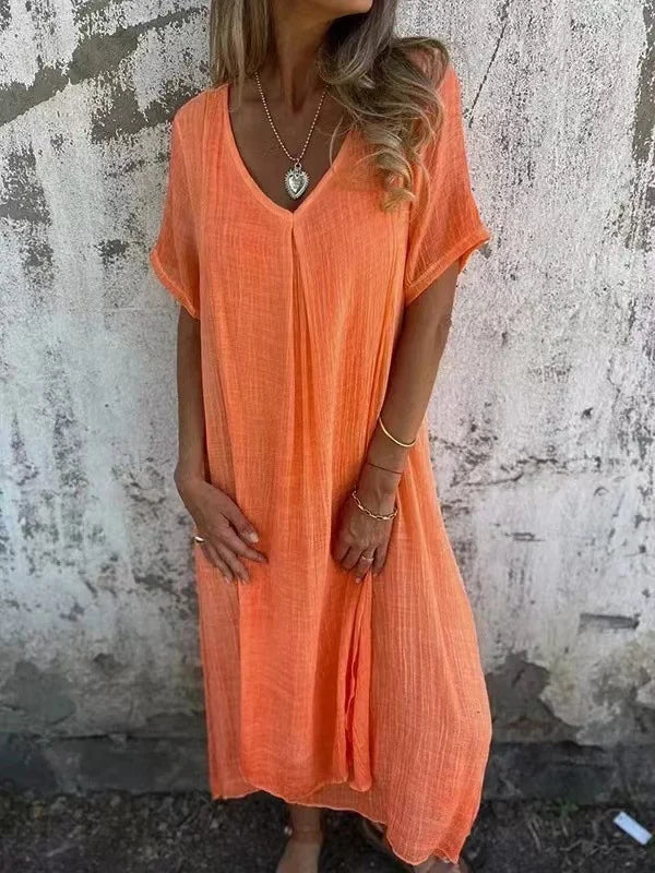 Orange V-neck dress with short sleeves, worn by a person in front of a textured wall.