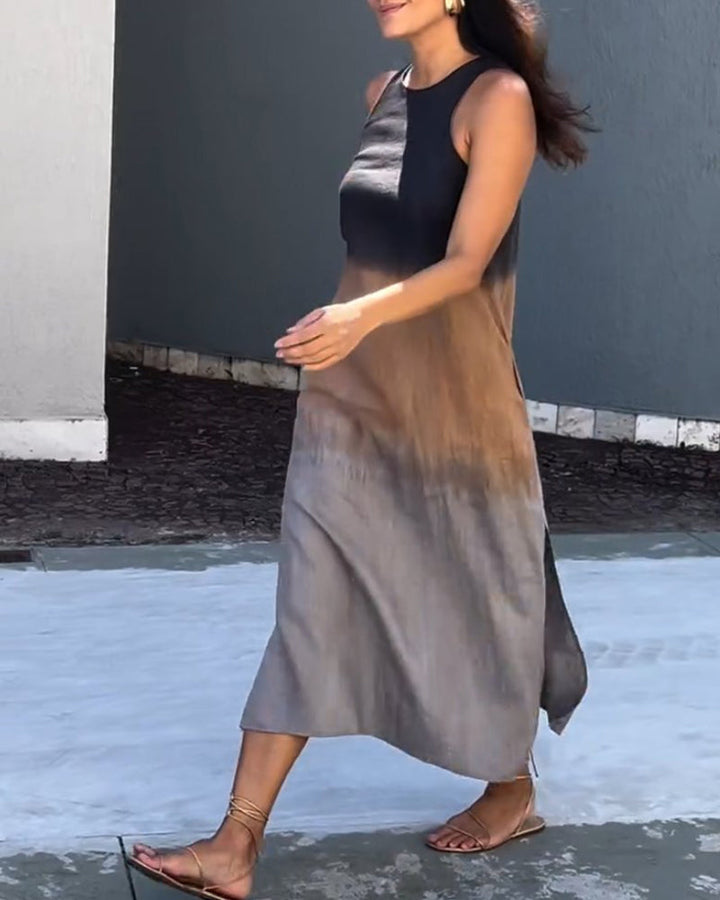 Woman wearing a sleeveless, ombre black to brown dress walking outside on a stone path.