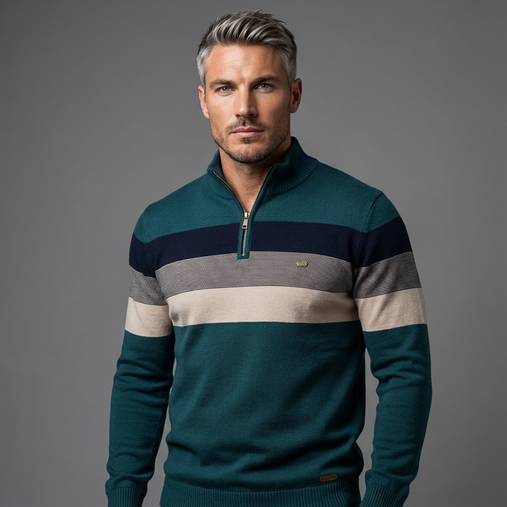 Man wearing a striped pullover with teal, navy, beige, and gray hues in a studio setting.