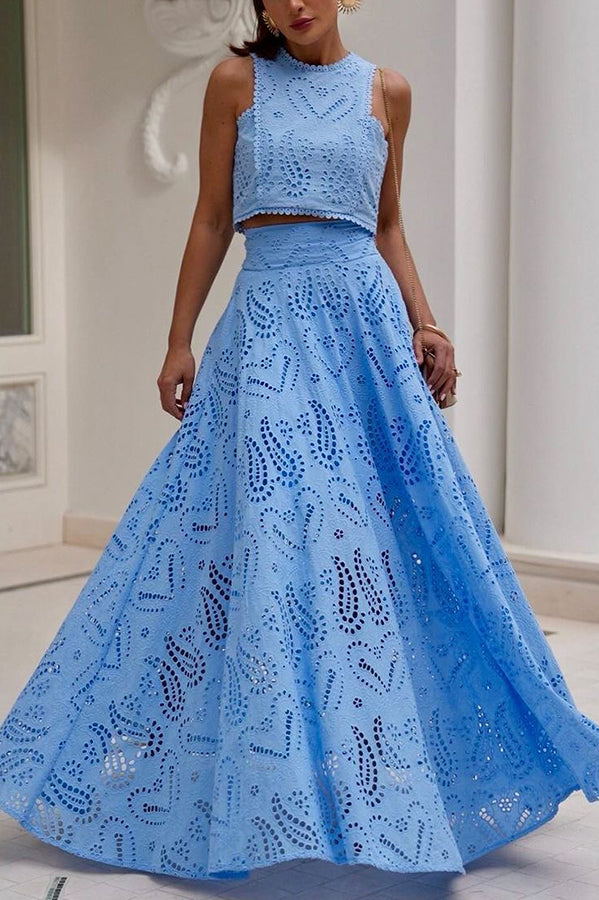 Woman posing in a blue embroidered maxi skirt and top set indoors with a classic decor background.