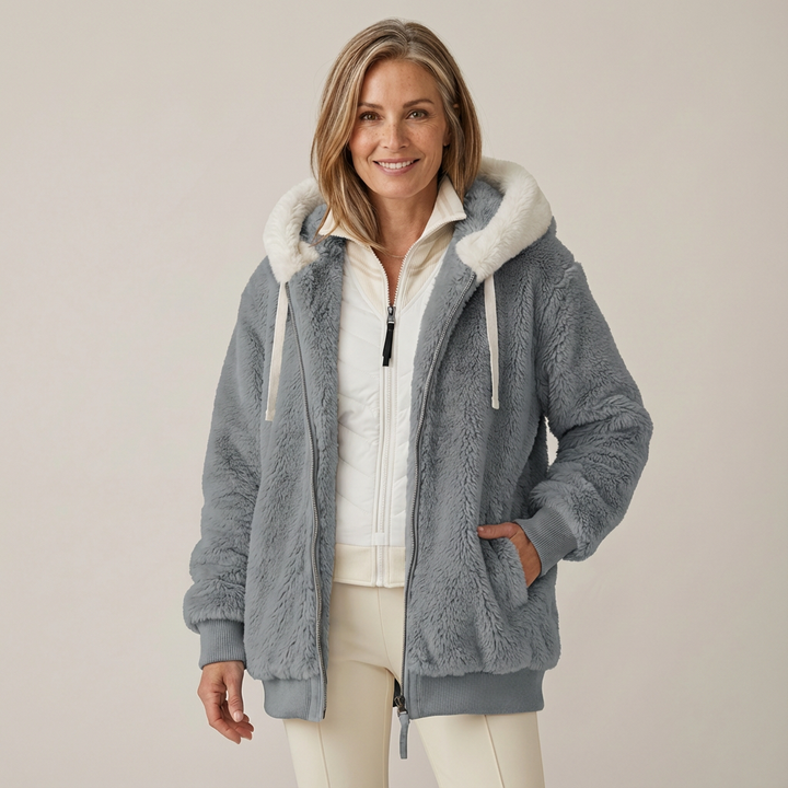 Woman wearing a fluffy gray hooded jacket with white lining, in a studio setting.
